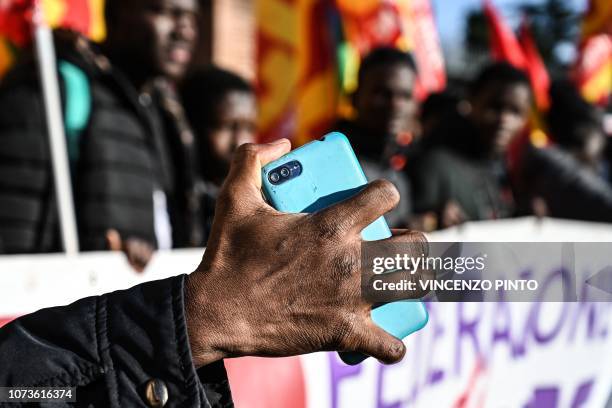 Migrants holds his mobile phone as people, members of anti-racism associations and migrants gather on Piazza della Repubblica in central Rome on...