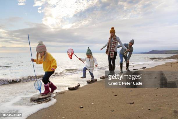 family walking on stepping stones on beach - caractéristiques côtières photos et images de collection