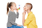 Cute young girl with speech therapist making special exercises at speech therapy office. Child speech therapy concept on white background. Speech impediment corrective exercises.