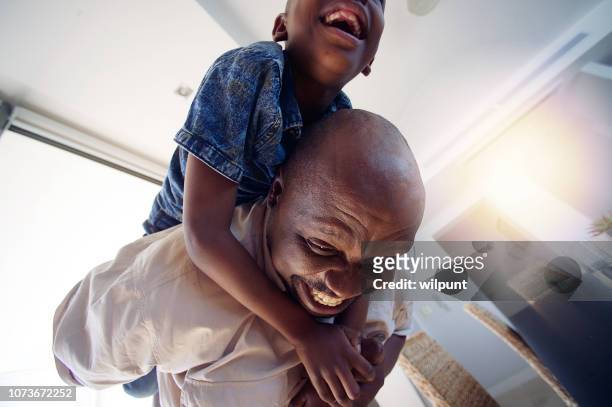 grandfather playing having fun with son on his back indoors fun - boys wrestling stock pictures, royalty-free photos & images