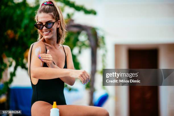 smiling woman holding suntain lotion - suntan lotion stock pictures, royalty-free photos & images