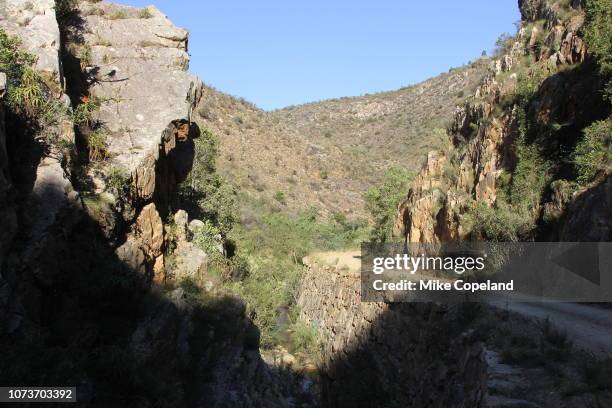 a bend in the narrow, winding gravel road on a rocky corner in a kloof on prince alfred's pass through the outeniqua mountains between knysna and avontuur in the western cape province of south africa. - avontuur foto e immagini stock