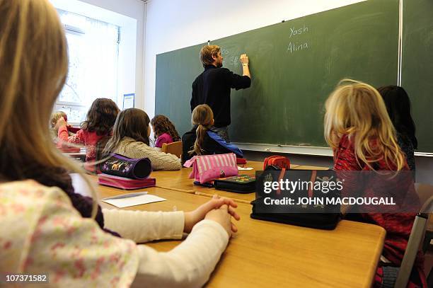 Teacher writes on the blackboard during class in a primary school in Berlin December 7, 2010. The three-yearly OECD Programme for International...