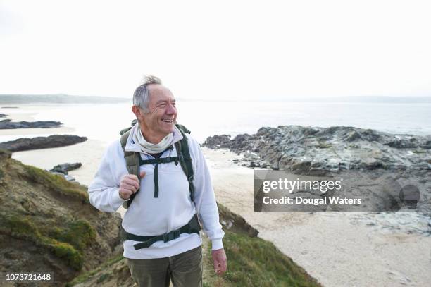 happy senior man hiking along coastline. - coastal feature stock pictures, royalty-free photos & images