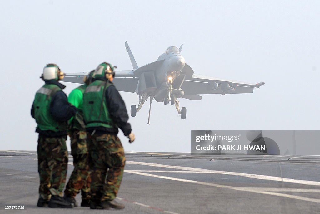 Crew members look at an F/A-18E Super Ho