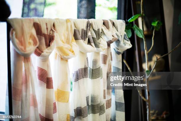 close up of selection of white hand dyed scarves with stripes and natural plant dye colours and patterns in a clothing store. - draped scarf stock pictures, royalty-free photos & images