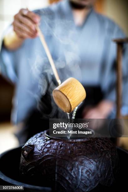 close up of traditional japanese tea ceremony, man using a hishaku, a bamboo ladle, to pour hot water. - tea ceremony stock pictures, royalty-free photos & images
