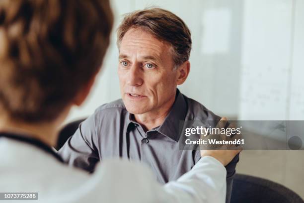 female doctor calming worried patient - man talking to doctor bildbanksfoton och bilder
