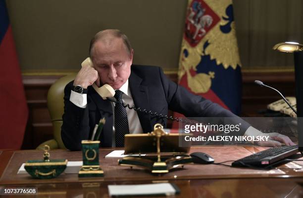 Russian President Vladimir Putin speaks on the phone in his office in Saint Petersburg on December 15, 2018 with Artyom Palyanov -- a boy with...
