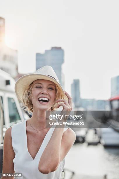 portrait of laughing young woman wearing a hat at a marina - high society stock pictures, royalty-free photos & images