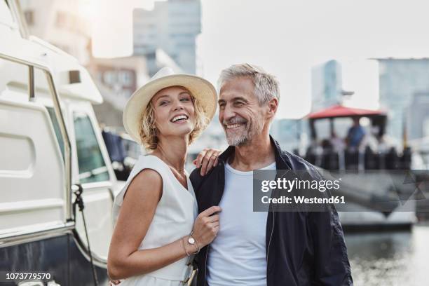 older man and young woman at a marina next to a yacht - yacht de luxe stock-fotos und bilder