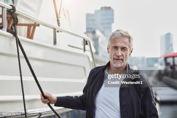 confident mature man at a marina next to a yacht - marina stock pictures, royalty-free photos & images