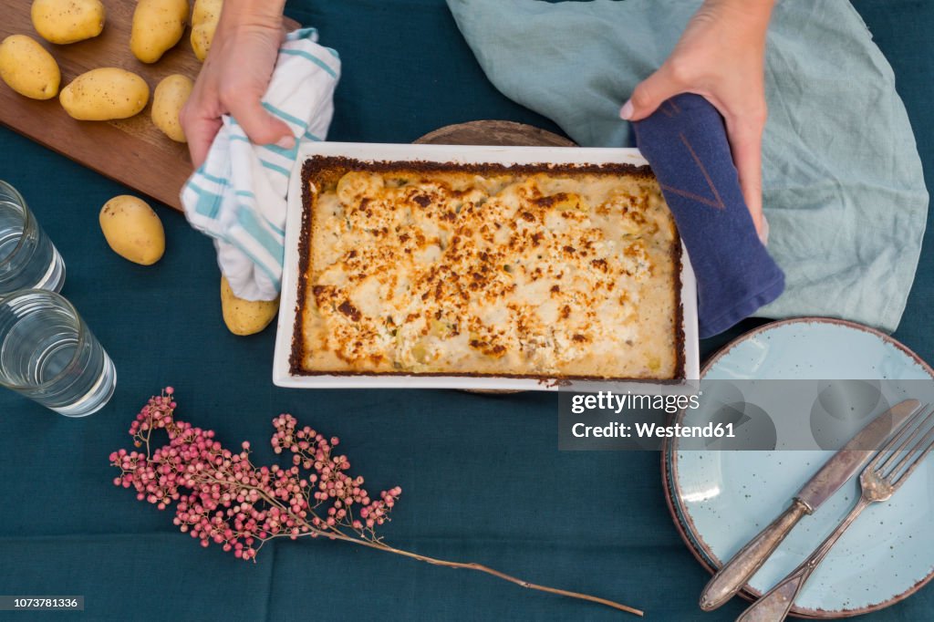 Woman serving potato mincemeat gratin, partial view