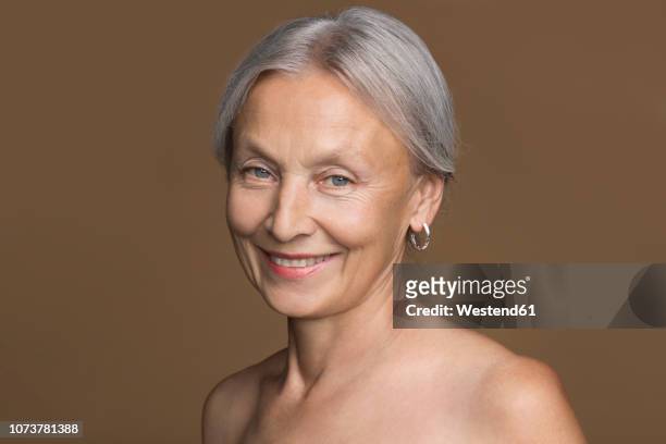 portrait of naked senior woman with grey hair in front of brown background - fundo castanho imagens e fotografias de stock