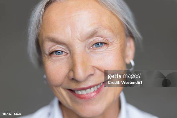 portrait of smiling senior woman with grey hair and blue eyes - smiling eyes stock pictures, royalty-free photos & images