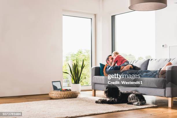 father playing with his son at home - baby hund innenaufnahme stock-fotos und bilder