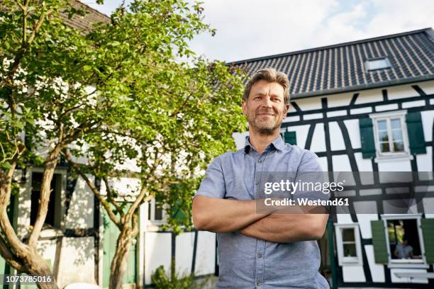 mature man standing in his garden wearing apron - mann stolz stock-fotos und bilder
