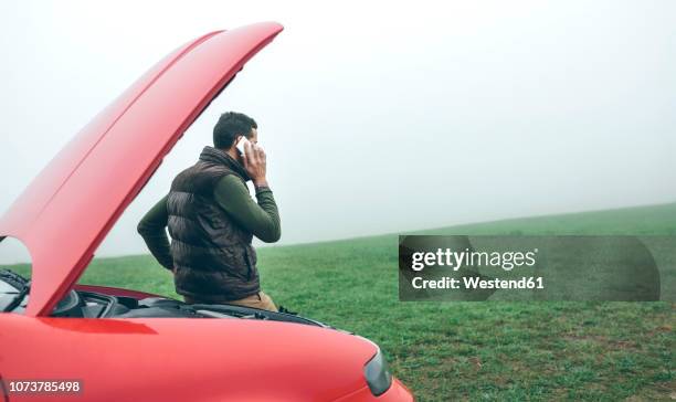 man talking on cell phone next to broken car - broken down car rural stock pictures, royalty-free photos & images