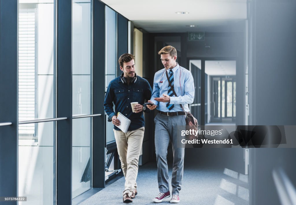 Two colleagues walking and talking on office floor