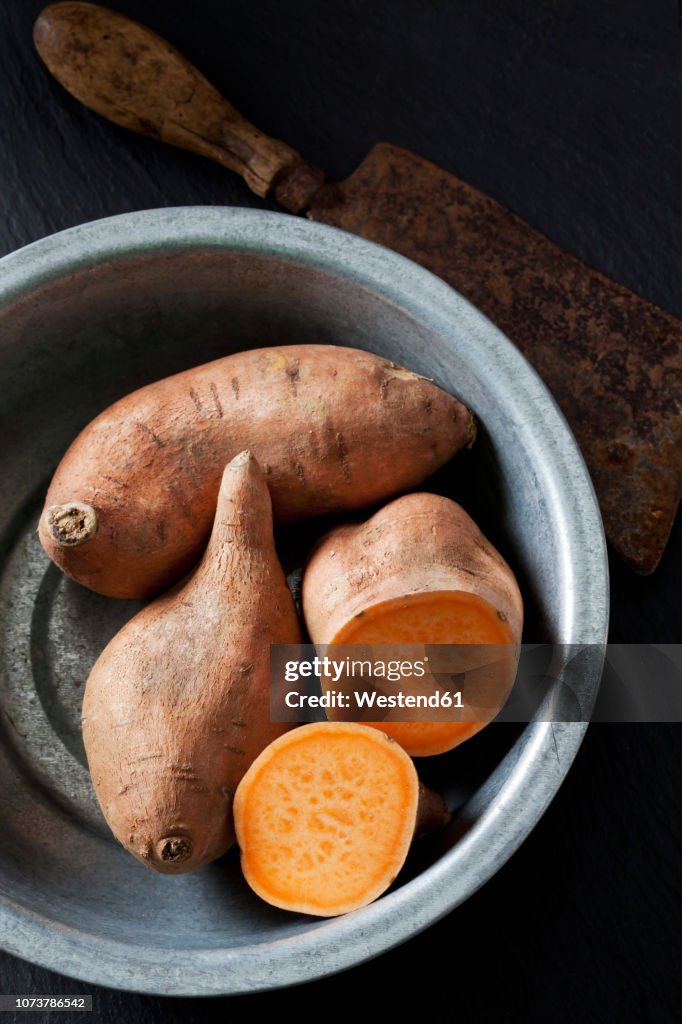 Sliced and whole sweet potato in metal bowl