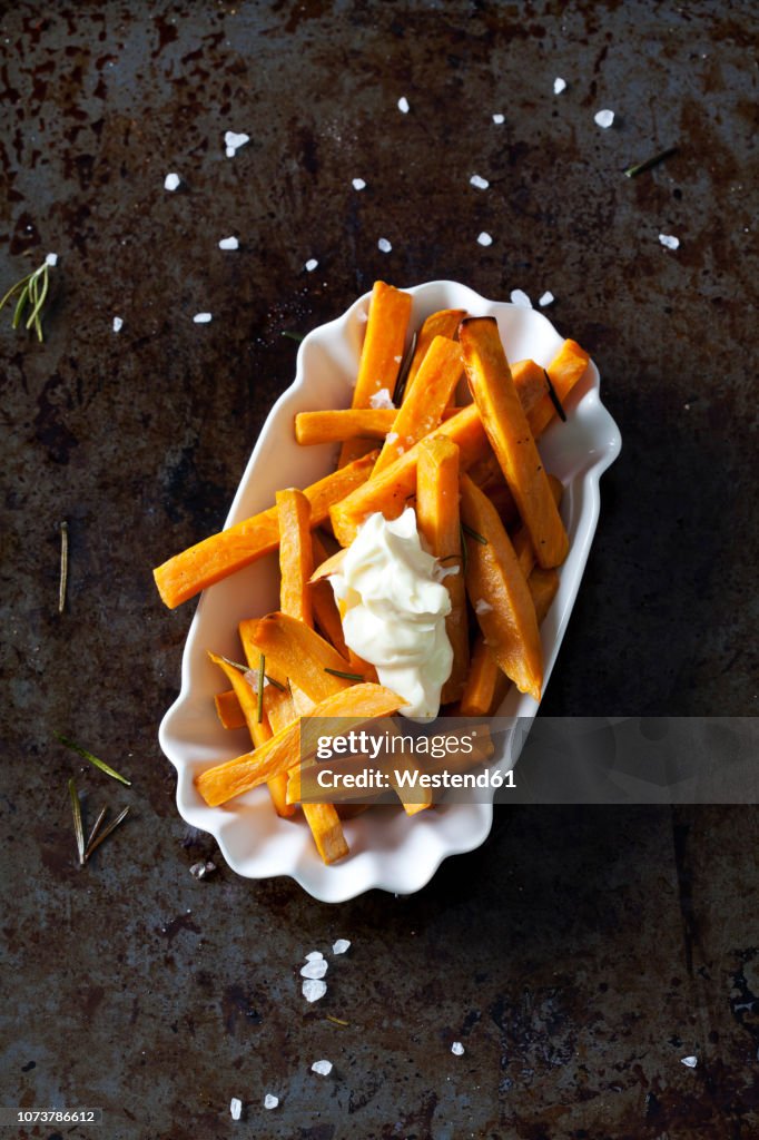 Salted sweet potato fries with rosmary and mayonnaise in porcelain bowl