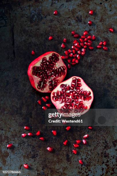 two halves of pomegranate and pomegranate seed on dark metal - pomegranate stock pictures, royalty-free photos & images