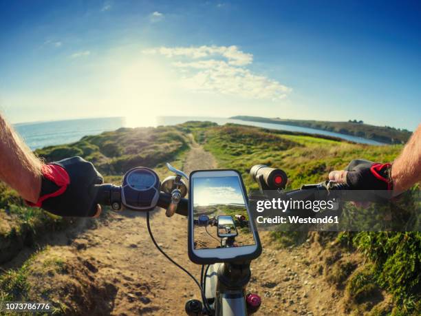 france, bretagne, sainte-anne la palud, plage de treguer, cell phone on mountain e-bike - mobile phone in hand driving stock pictures, royalty-free photos & images