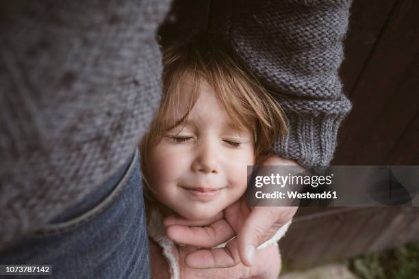portrait of blond little girl with eyes closed standing beside her father - human head photos et images de collection