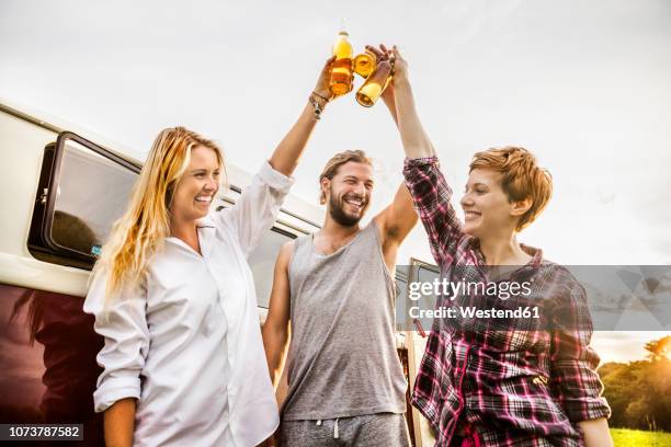 happy friends clinking beer bottles at a van in rural landscape - drinking bier stock-fotos und bilder