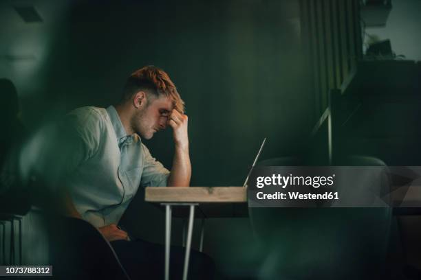 tired man sitting in office, working late in his start-up company - hoffnungslosigkeit stock-fotos und bilder