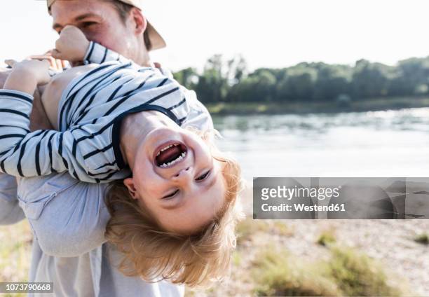 father and son having fun at the riverside - disfrutar naturaleza fotografías e imágenes de stock