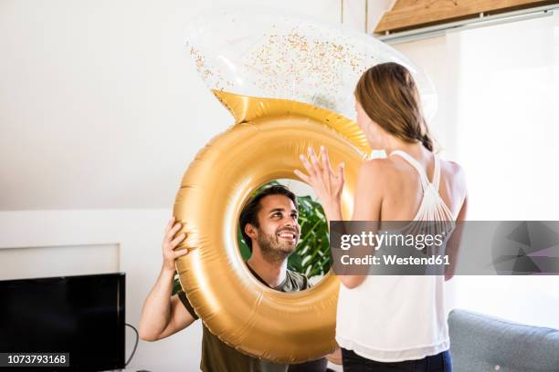 smiling man looking at girlfriend through large inflatble ring at home - woman putting on diamond stock pictures, royalty-free photos & images