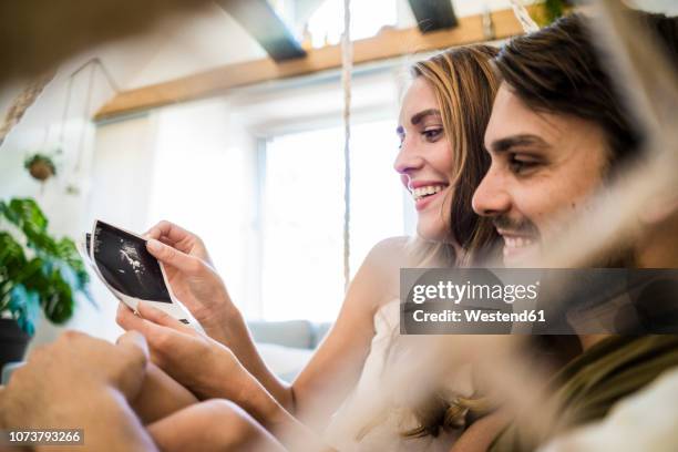 happy couple looking at ultrasound scans - verhütungsmittel stock-fotos und bilder