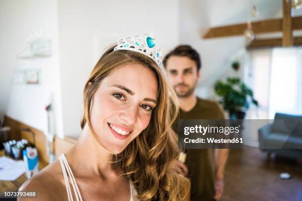 portrait of smiling woman wearing tiara at home with man in background - woman crown stock pictures, royalty-free photos & images