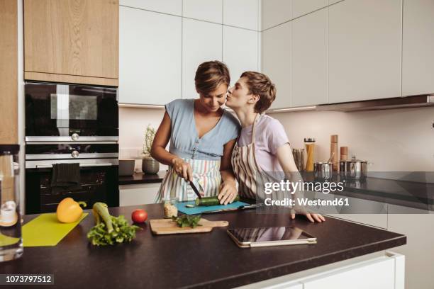 happy lesbian couple in kitchen cooking together - photos of lesbians kissing stock pictures, royalty-free photos & images