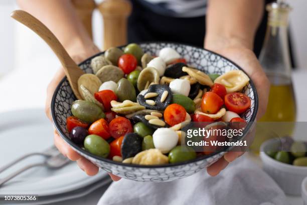 woman showing mediterranean orecchiette with tomato, olives and mozzarella - mediterranean food fotografías e imágenes de stock