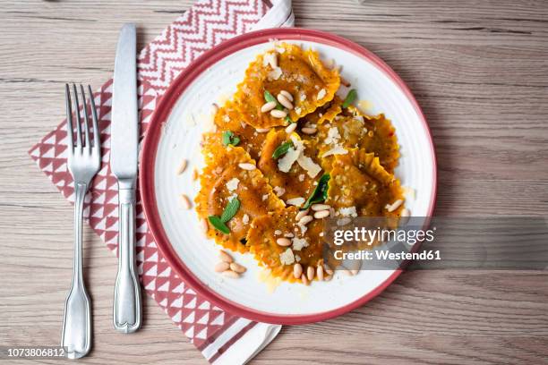 plate of pumpkin ravioli with sage leaves, parmesan and pine nuts - ravioli foto e immagini stock