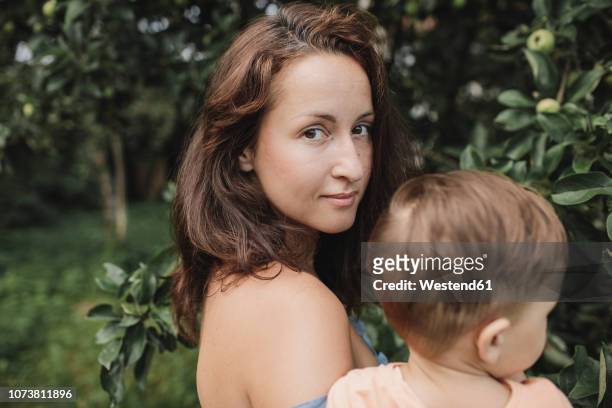 portrait of mother with baby in garden - off shoulder stock-fotos und bilder