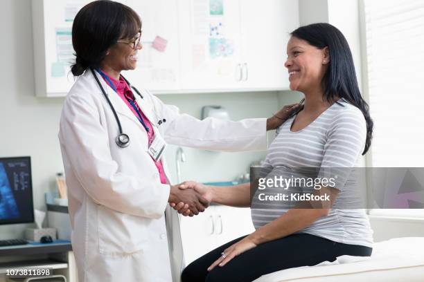 female doctor greeting pregnant patient at clinic - pregnant women greeting stockfoto's en -beelden