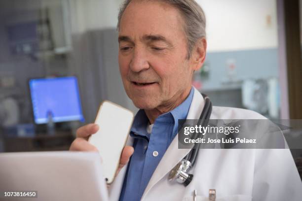 doctor dictating patient notes to a smartphone - diktera bildbanksfoton och bilder