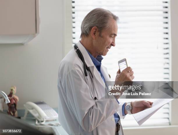 doctor dictating patient notes to a smartphone - diktera bildbanksfoton och bilder