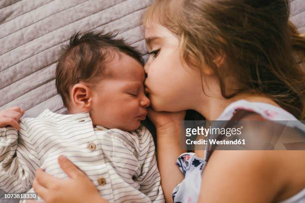 affectionate girl lying on blanket cuddling with her baby brother - baby girls stock-fotos und bilder