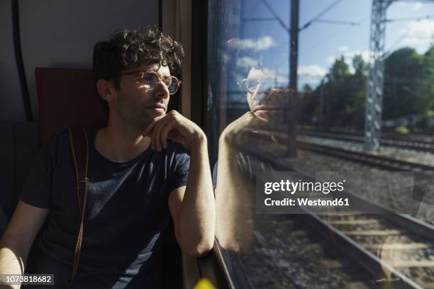 man traveling by train looking out of window - trem imagens e fotografias de stock