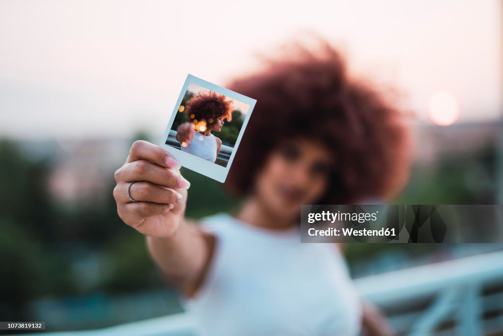 Young woman showing instant photo of herself, close-up