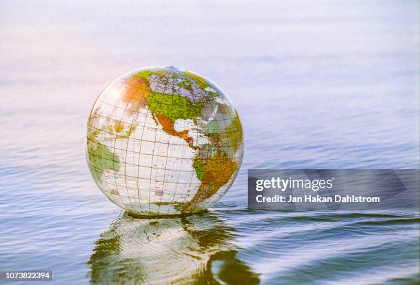 close-up of plastic globe floating on water - world politics stock pictures, royalty-free photos & images