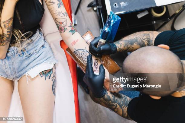 tattooist drawing on arm of customer - tattooing ストックフォトと画像
