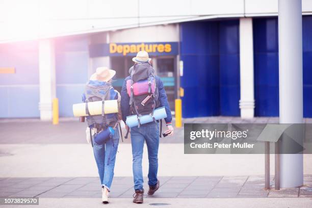 backpacker couple entering airport - backpacker airport stock pictures, royalty-free photos & images