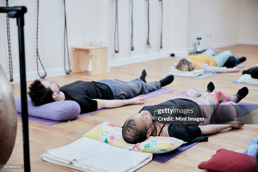 People lying down on an exercise studio floor relaxing after a sound therapy session