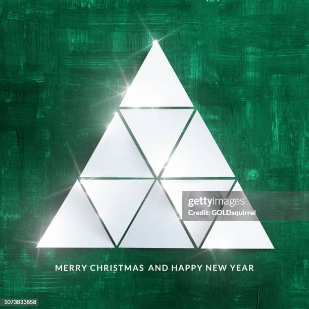 triangular sheets of paper lying on a hand-made painted green background - unique modern christmas illustration with abstract christmas tree light and shadows and textures and 3d effect - christmas tree close up stock illustrations