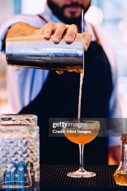 bartender pouring whiskey cocktail into glass with sugared rim - cocktail shaker stock pictures, royalty-free photos & images